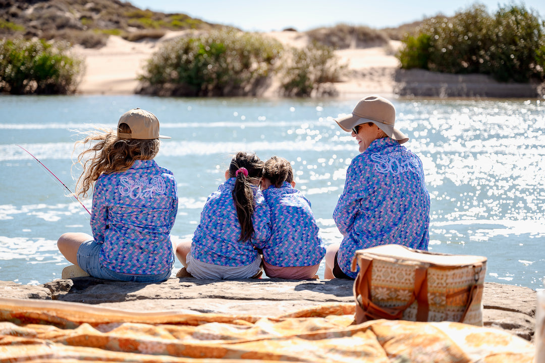 Mermaid Scales Fishing Shirt - Group of four seated on rocks by water, back lifestyle